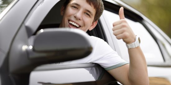 teen driver in good mood with black car selective focus on eyes